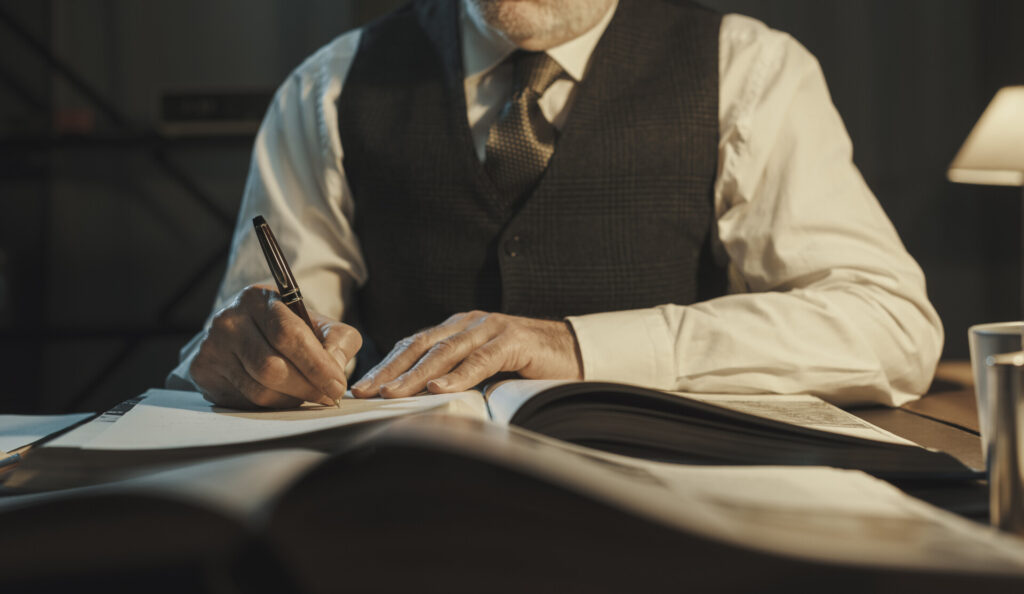Academic professor writing down notes and reading a book